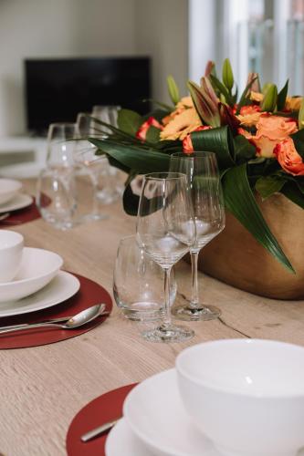 a table with wine glasses and a vase with flowers at Vakantiewoning De Curiositeit in Geraardsbergen
