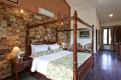 a bedroom with a bed and a stone wall at Tree of Life Ramvilas, Bandhavgarh in Tāla