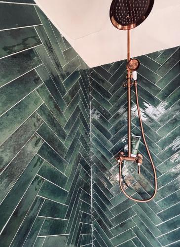 La salle de bains est pourvue d'un mur carrelé vert et d'une douche. dans l'établissement La Biscornue, à Lauris