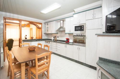 a kitchen with a wooden table and a dining room at AG Piso Río Miño Carballo, a 700m del centro in Carballo