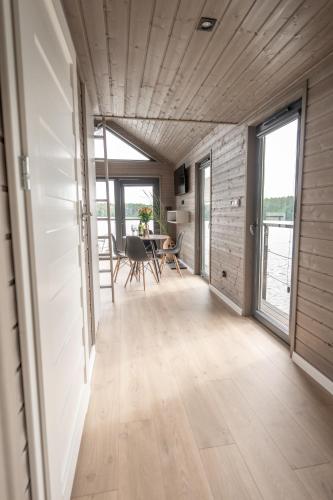 a living room with a table and chairs and windows at Domki na wodzie - Mazury in Ruciane-Nida