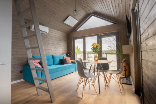 a room with a blue couch and a table and chairs at Domki na wodzie - Mazury in Ruciane-Nida
