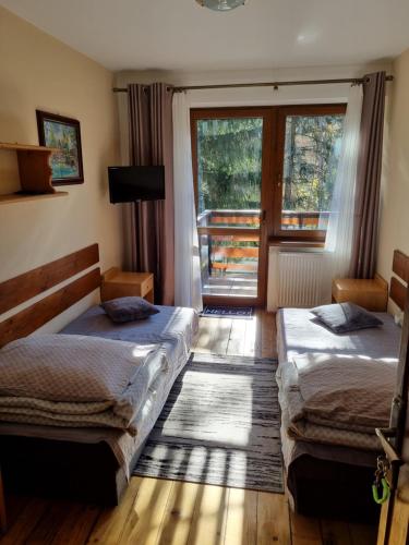 deux lits dans une chambre avec une fenêtre dans l'établissement Kwatery u Janka, à Zakopane