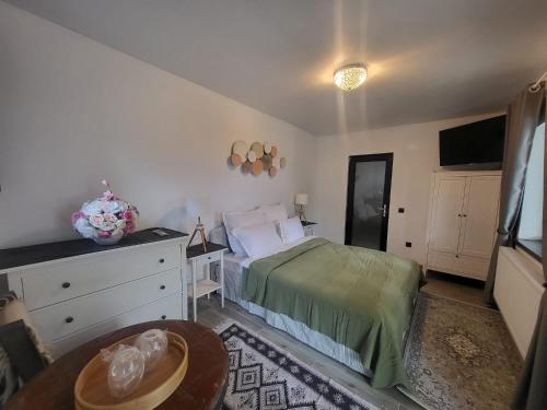 a bedroom with a bed and a dresser and a table at Pensiunea Casa Dacilor in Podeni