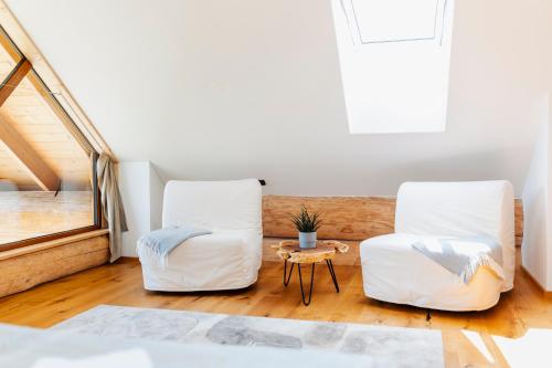 two white chairs and a table in a room at Log Garden Estate in Dobrova
