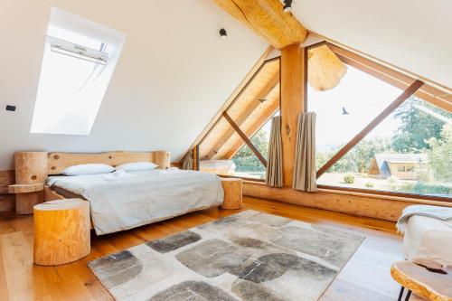 a bedroom with a bed and a large window at Log Garden Estate in Dobrova