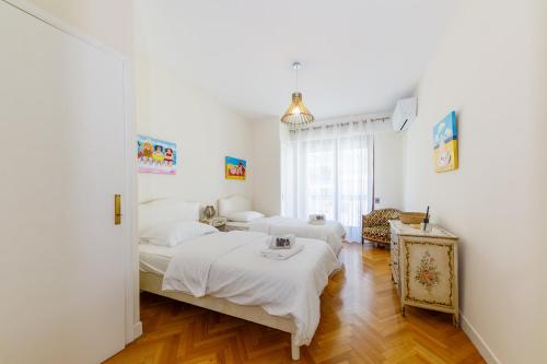 deux lits dans une chambre aux murs blancs et au parquet dans l'établissement Palais D'orient, à Nice