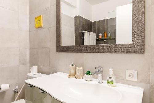 une salle de bain blanche avec un lavabo et un miroir dans l'établissement Palais D'orient, à Nice