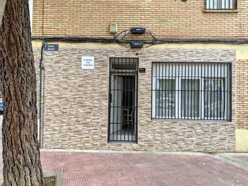 Un edificio de ladrillo con una puerta con ventanas enrejadas en Como en casa, en Parla