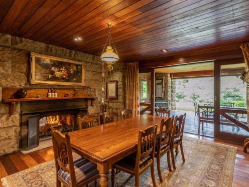 a dining room with a wooden table and a fireplace at Glentowy Farm Underberg in Underberg