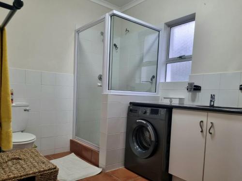 a bathroom with a washing machine and a shower at 'Top Flat' Apartment with Easy Beach Access, Sea front sleeps 5 in Gordonʼs Bay