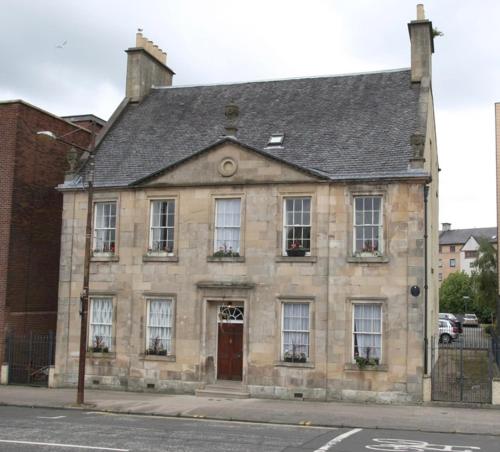 an old stone building on a city street at 52, Charlotte Street Apartments in Glasgow
