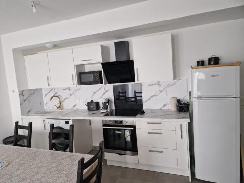 une cuisine avec des armoires blanches et un réfrigérateur blanc dans l'établissement Appart T3 proche mer, à Frontignan