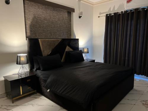 a bedroom with a bed with a black headboard at Luxor Apartments & Suites - DHA Phase 9 in Lahore