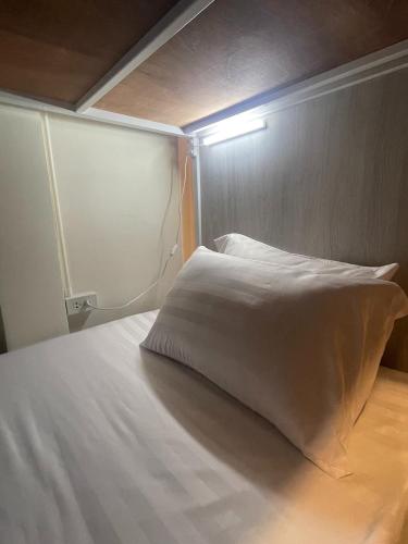 a white pillow sitting on a bed in a room at Round The Clock Hostel in Samphanthawong