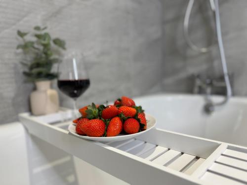 a bowl of strawberries and a glass of wine on a shelf at Modern Two-Bedroom Flat in Swindon