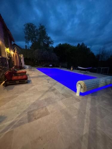 a large blue swimming pool in a yard at night at L'ancienne Epicerie de POIL in Poil