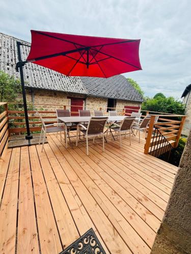 a wooden deck with a table and chairs and a red umbrella at L'ancienne Epicerie de POIL in Poil
