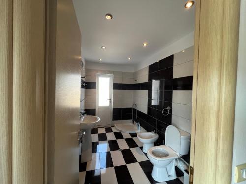 a bathroom with two toilets and a checkered floor at Apartment room Noar in Përmet