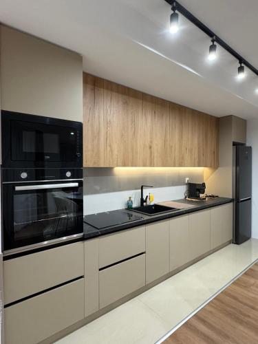 a kitchen with black appliances and wooden cabinets at Luma Apartment in Bitola