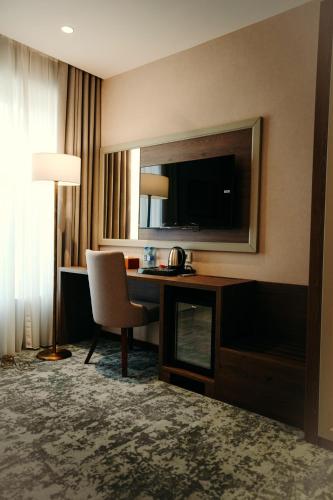 a hotel room with a desk and a television at Hill Chalet Hotel Gabala in Gabala