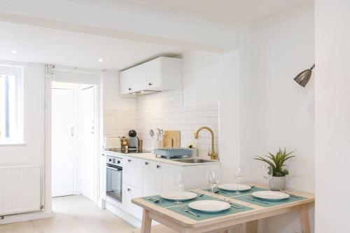 a white kitchen with a table with plates on it at Central quiet cottage Walk to shops, bars & beach in Brighton & Hove