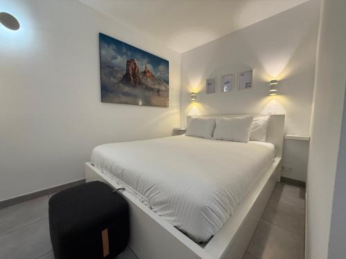 a white bedroom with a white bed and a black chair at Exclusive Holiday - Edifico Paraiso Maspalomas in San Fernando