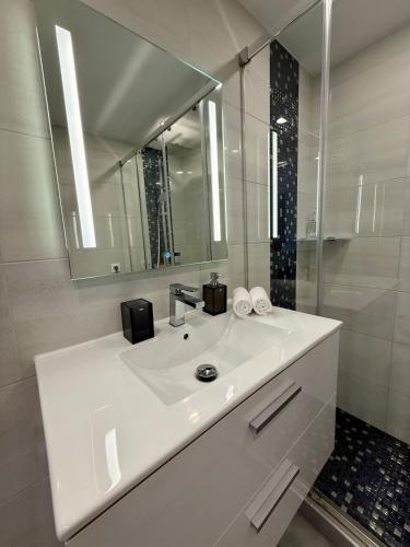 a white bathroom with a sink and a mirror at Exclusive Holiday - Edifico Paraiso Maspalomas in San Fernando