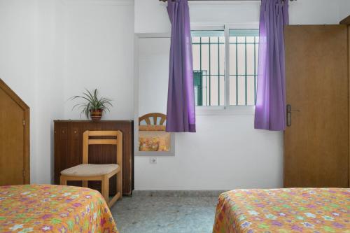 a bedroom with two beds and a window with purple curtains at Casa Paqui Bustos 1 in Conil de la Frontera
