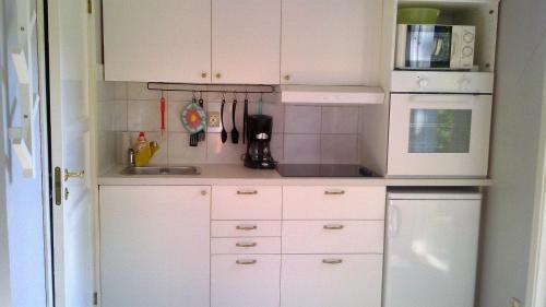 a small kitchen with white cabinets and a microwave at Pärlebo in Mellbystrand