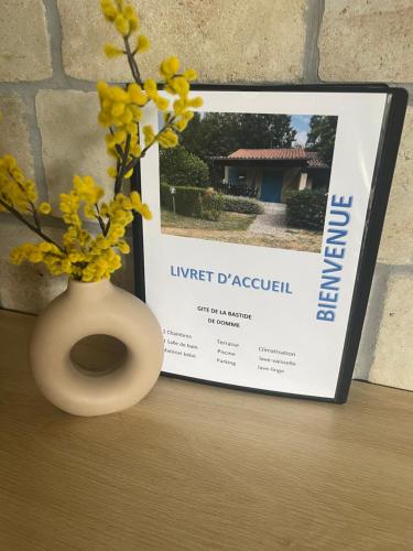 a vase with yellow flowers in it next to a sign at Gîte de la Bastide de Domme in Domme