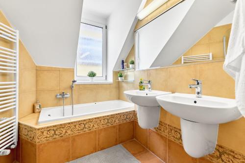 a bathroom with two sinks and a tub and a window at Apartmán Karlstadt in Karlovy Vary