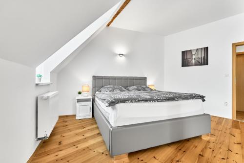 a bed in a white room with a wooden floor at Apartmán Karlstadt in Karlovy Vary