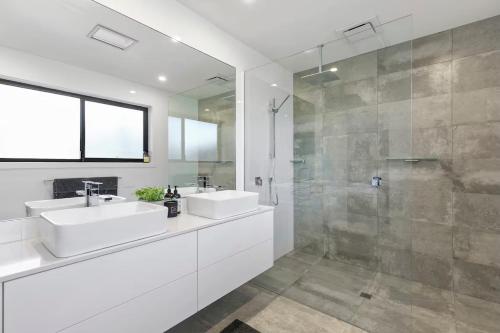 a white bathroom with two sinks and a shower at Coastal Escape on Highlander in Torquay