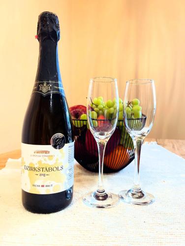 a bottle of wine and two wine glasses on a table at Rasiņas in Cesvainieki