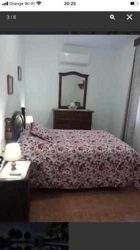 a bedroom with a bed with a red blanket and a mirror at Welcoming chalet with lake and mountain view - El Gastor in El Gastor
