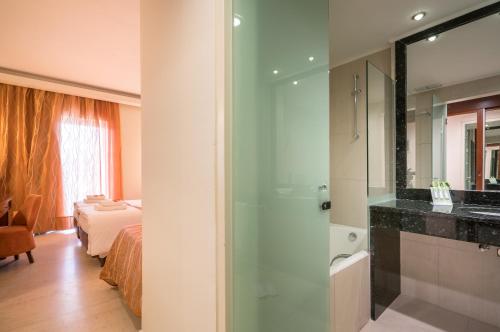 a bathroom with a shower and a bedroom with a bed at Zante Park Resort & Spa BW Premier Collection in Laganas