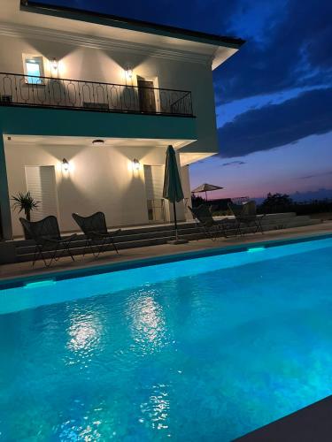 a swimming pool in front of a house at night at Vila sa bazenom Vrnjačka Idila in Vrnjačka Banja