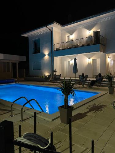 a large swimming pool in front of a house at night at Vila sa bazenom Vrnjačka Idila in Vrnjačka Banja