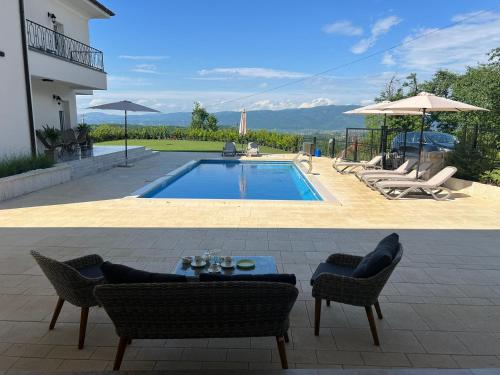 a swimming pool with chairs and a table and a house at Vila sa bazenom Vrnjačka Idila in Vrnjačka Banja
