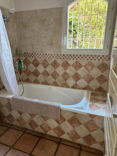 La salle de bains est pourvue d'une baignoire et d'une fenêtre. dans l'établissement Villa vue mer Mandelieu 4 chambres, à La Celle-sous-Gouzon