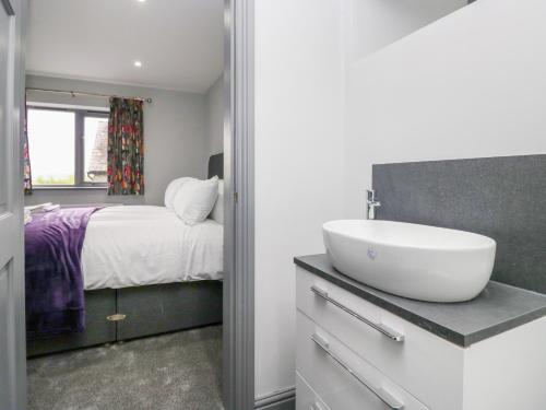 un bagno con lavandino e un letto con finestra di Fell View Cottage a Kendal