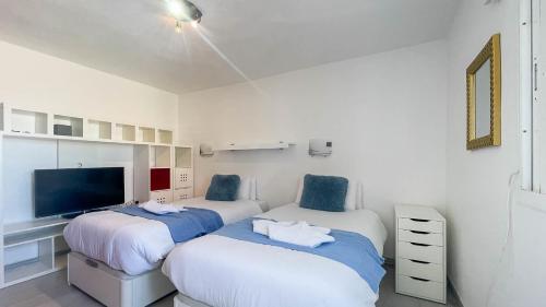 a bedroom with two beds and a flat screen tv at Caideros Sunset in Los Caideros