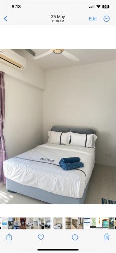 a bed with white sheets and a blue towel on it at By The Sea in Batu Ferringhi