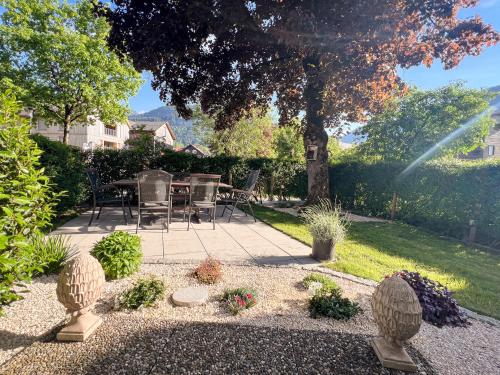 a patio with a table and chairs under a tree at D`Alpenapartments Bezau in Bezau