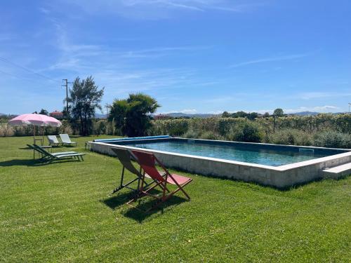 a swimming pool with two lawn chairs and an umbrella at El Patio in San Vito Rimini