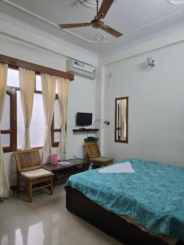 a bedroom with a bed and two chairs and a television at Besillio Grand Hotel & Restaurant in Sundarnagar