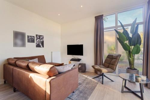 a living room with a brown couch and a tv at Luxe Chalet 211-25 in Hulshorst aan het water! in Hulshorst