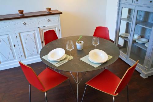 un tavolo da pranzo con sedie rosse e un tavolo con bicchieri di Lumiae Suite a Lecce