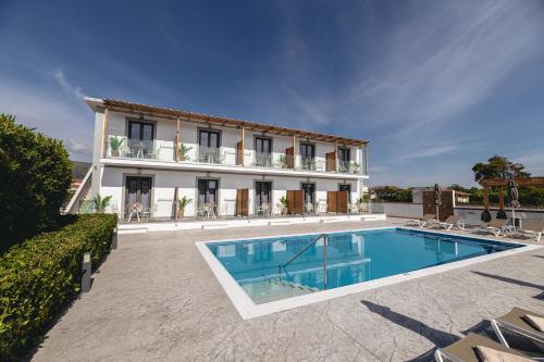 a villa with a swimming pool in front of a building at White Canvas Boutique Studios in Laganas
